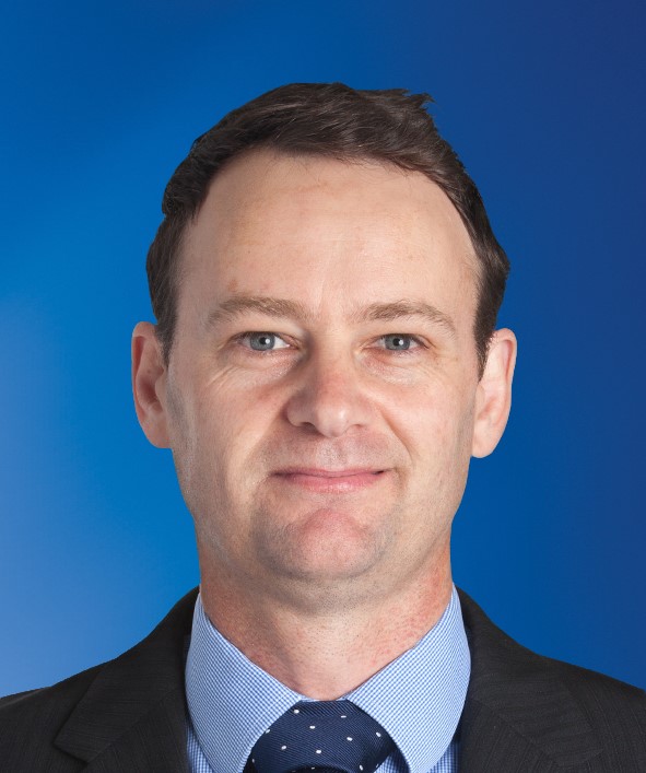 Brian Richardson standing in a field of sheep